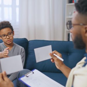 African American school psychologist conducting psychological assessment of a boy, child therapy